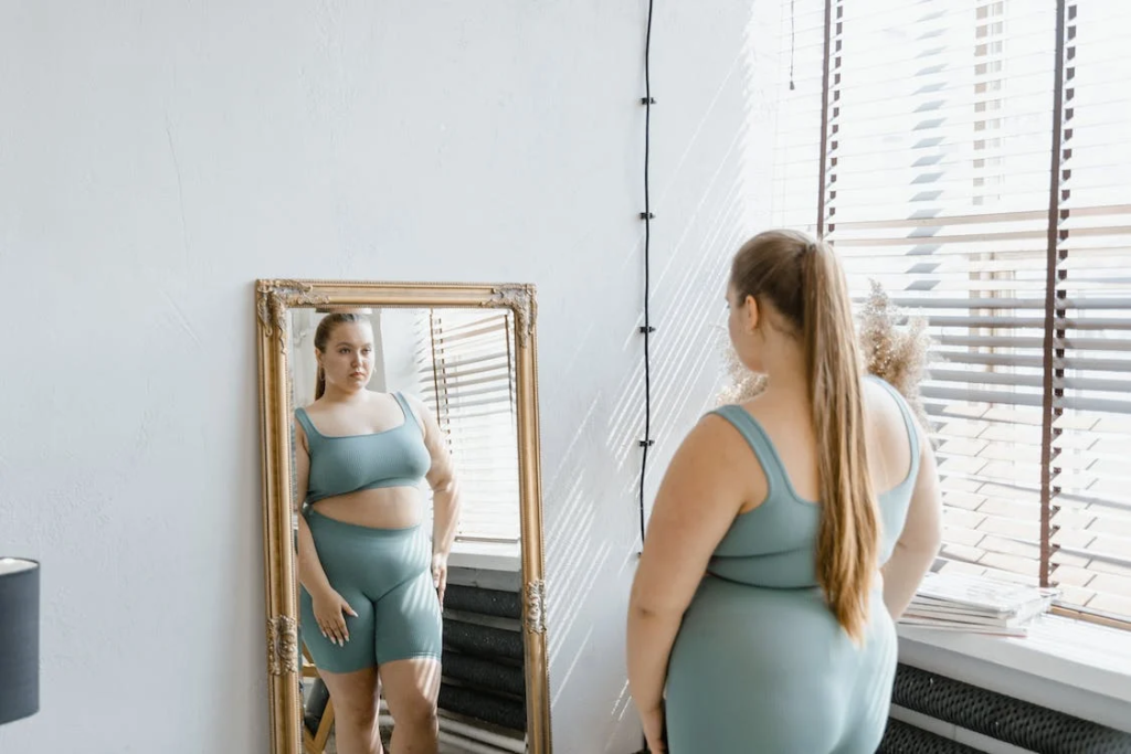 mulher gorda exercitando a autoaceitação feminina em frente ao espelho